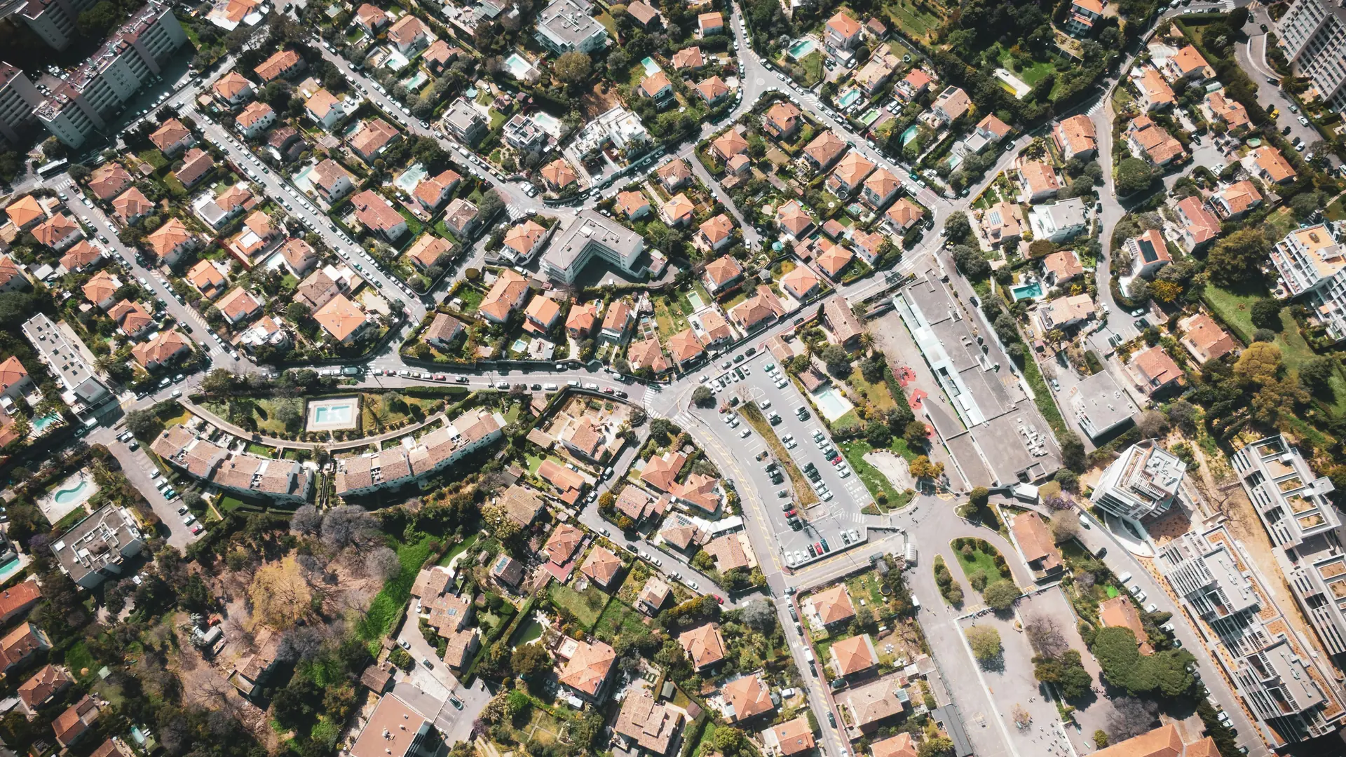 Vista aérea de um bairro residencial arborizado, com casas, ruas e uma quadra de esportes
